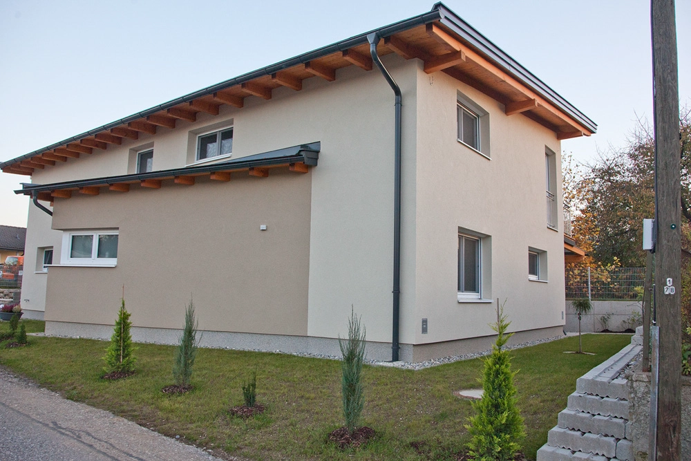 Ferienwohnung Greiler – Außenaufnahme; von einer Immobilie in Kärnten, schönes kleines Haus in weiß und hellbraun, mit Garten und kleinen Bäumen und Zaun.